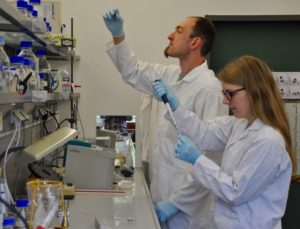 Auf diesem Foto sehen Sie zwei Studenten beim Pipettieren.